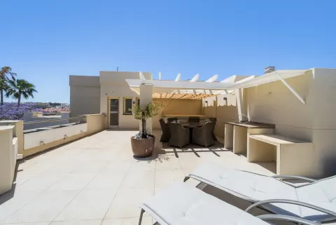 A second terrace with a pergola over a dining table, loungers in the sun