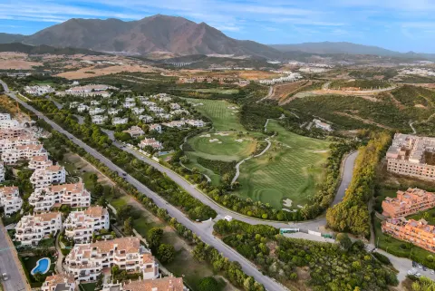 Homes and a golf course from the air, the mountains behind